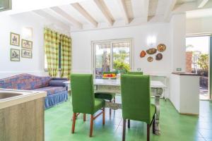 a kitchen and living room with a table and green chairs at Casa Orchidea in Calatabiano