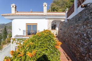 a house with a stone wall and orange flowers at Casa rural Villena in Frigiliana