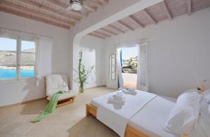 a white bedroom with a bed and a view of the ocean at Villa Crysta Mykonos in Mikonos +50 photos