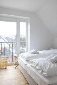 a white bedroom with two beds and a large window at Strandhafer in Böhl