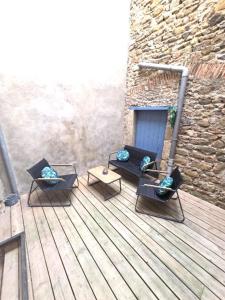 three chairs and a table on a wooden deck at La Traboule - Terrasse - 6 pers in Saint-Germain-Lembron