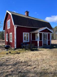 a red barn with a table and chairs in front of it at Enskilda stugan in Kärsta