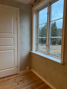 an empty room with two windows and a wooden floor at Enskilda stugan in Kärsta