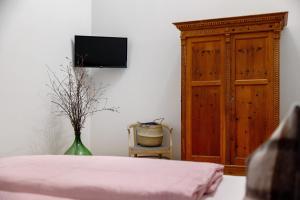 a bedroom with a bed and a tv and a cabinet at Herzleierhof Rodeneck in Rodengo