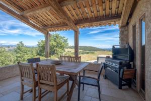 a wooden table and chairs on a patio with a grill at Maison Time-out in Villevieille