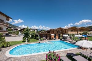 a pool at a resort with chairs and umbrellas at Chalet Schaller in Missiano