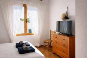 a bedroom with a television on a wooden dresser at Apartamento Natalia in Menorca