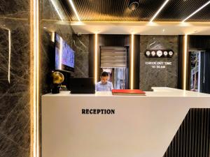 a person sitting at a reception desk with a laptop at Hotel National - Grant Road in Mumbai