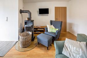 a living room with a chair and a couch and a tv at Vogelsberger Bett Köddingen in Köddingen