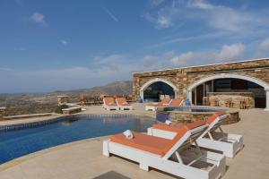 a villa with a swimming pool and lounge chairs at Aegean Villas Ios in Ios Chora