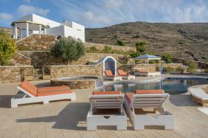 a villa with a swimming pool with lounge chairs at Aegean Villas Ios in Ios Chora