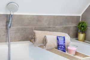 a bathtub with towels and a glass of pink liquid at Deluxe Apartment in Duisburg +14 photos