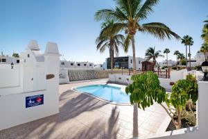 a swimming pool with palm trees on a patio at Casa Gloria in Puerto del Carmen