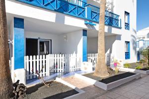 a white house with blue columns and a white fence at Casa Gloria in Puerto del Carmen