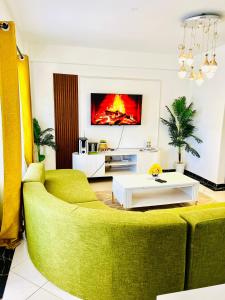 a living room with a green couch and a tv at Bethany Cushy Home Ltd in Kisii