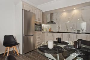 a kitchen with a table and a stainless steel refrigerator at Helios Apartment 2 in Karpathos +8 photos
