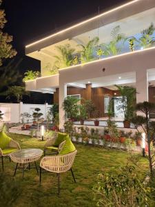 a house with chairs and a table in a yard at Kaashi Flora Whitehouse-9BHK in Varanasi