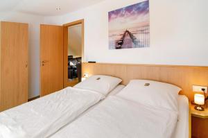 a bedroom with two white beds and a picture on the wall at Huus Nördernee 2 in Norderney