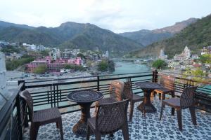 ein Balkon mit Tischen und Stühlen und Blick auf eine Stadt in der Unterkunft Full Stop Hostel in Rishikesh