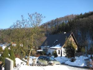 a house with a car parked in the snow at Haus Am Waldrand in Freital