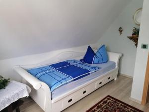 a white bed with blue pillows in a room at Haus Am Waldrand in Freital