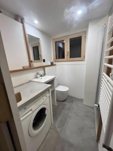 a bathroom with a washing machine and a toilet at Au Soleil in Séez