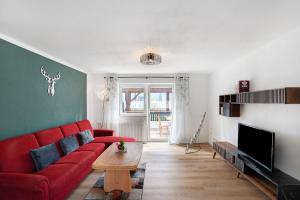 a living room with a red couch and a tv at Wohnung zum Hirschen in Gräfelfing