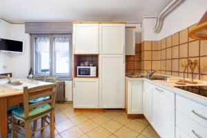 a kitchen with white cabinets and a table and a microwave at Lovin Summer in Livigno