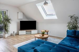 a living room with a blue couch and a tv at Fewo Ebringen Vogesenblick in Ebringen