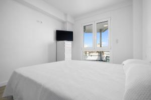 a white bedroom with a white bed and a window at Formentor 863 in Salou