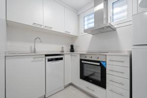 a white kitchen with white cabinets and an oven at Formentor 863 in Salou