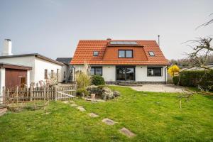 a house with an orange roof and a yard at 5 Sterne Ferienwohnung Boddenblick in Glowe