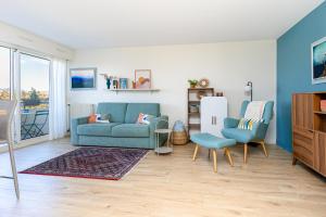 a living room with a blue couch and two chairs at Appart Anglet in Anglet