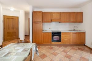 an empty kitchen with wooden cabinets and a table at Residence Malibu Appartamento 7 in Falcade +16 photos