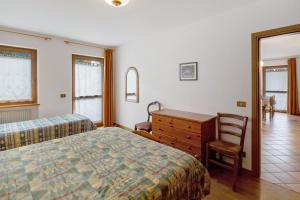 a bedroom with a bed and a desk and a chair at Residence Malibu Appartamento 7 in Falcade