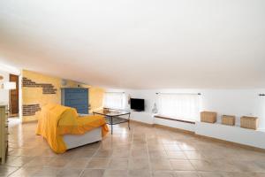a living room with a yellow blanket on a couch at Giojas125 Monolocale per 4 persone in Orosei