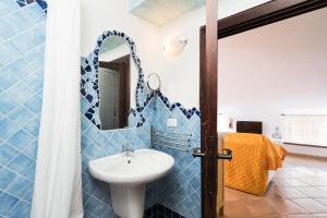 a blue tiled bathroom with a sink and a mirror at Giojas125 Monolocale per 4 persone in Orosei +13 photos