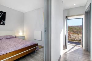 ein Schlafzimmer mit einem Bett und einer Glasschiebetür in der Unterkunft Casaesquerda Cinza in Vieira do Minho
