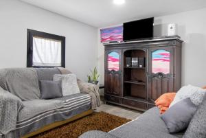 ein Wohnzimmer mit Sofa und Entertainment-Center in der Unterkunft Casaesquerda Cinza in Vieira do Minho