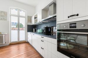 a kitchen with white cabinets and a stove top oven at Wohnoase im Denkmal in Garding +13 photos
