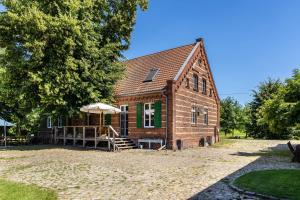 an old brick barn with a porch and stairs to it at Der Flusshof, Ferienhaus in Werben