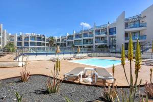 a swimming pool with two lounge chairs next to a building at Oceanfront Apartment With Pool in El Cotillo