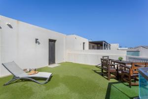 a balcony with a chair and a table and grass at Oceanfront Apartment With Pool in El Cotillo