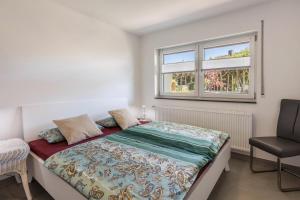 a bedroom with a bed and a chair and two windows at Ferienwohnung am Bregenberg in Bräunlingen