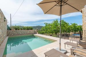 a swimming pool with an umbrella and a table and chairs at Son Sant Joan in Alaró