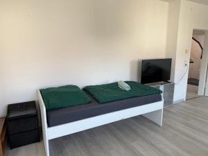 a bed with green sheets and a television in a room at Schöne 3 Zimmer Wohnung in Bad Salzuflen in Bad Salzuflen +4 photos