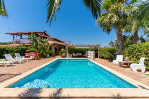 a swimming pool with palm trees and a house at Villa Relax in Galatone