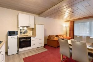 a kitchen with white cabinets and a table with chairs at Haus Erika in Stryck