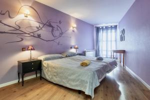 a bedroom with a bed with a branch mural on the wall at La Casa De Anta in Asturianos