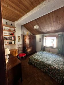 a bedroom with a bed and a desk and a window at Trilocale Einaudi Bardonecchia in Bardonecchia